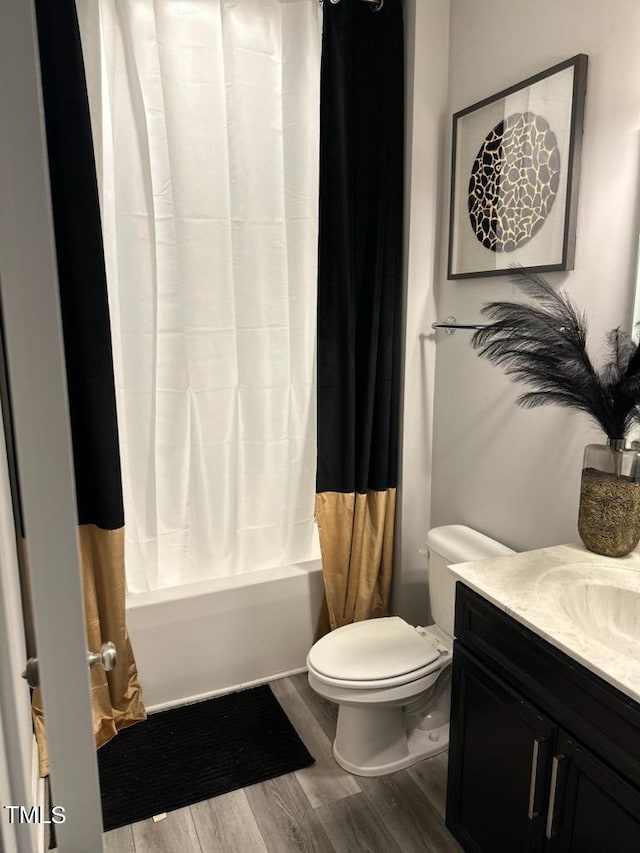 full bathroom featuring toilet, shower / bathtub combination with curtain, wood finished floors, and vanity