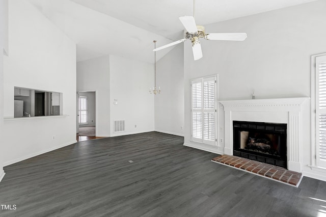 unfurnished living room with visible vents, a brick fireplace, wood finished floors, high vaulted ceiling, and ceiling fan with notable chandelier