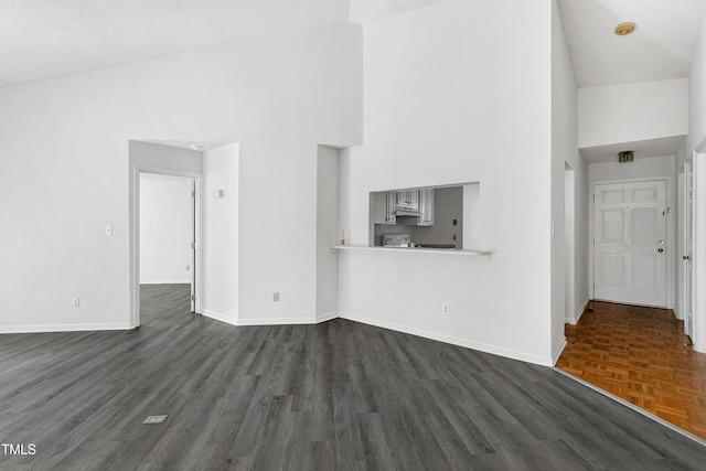 unfurnished living room featuring parquet floors, high vaulted ceiling, and baseboards