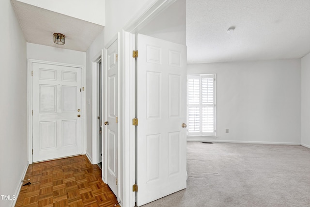 corridor featuring a textured ceiling and baseboards