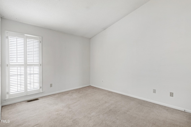 spare room featuring carpet, visible vents, and baseboards