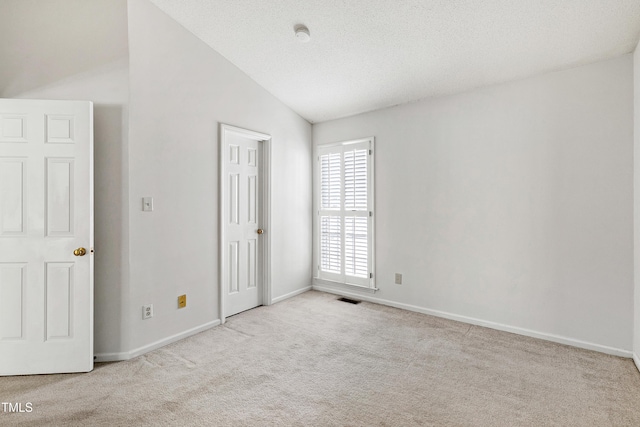 unfurnished bedroom featuring a textured ceiling, visible vents, baseboards, vaulted ceiling, and carpet