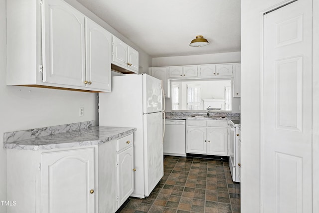 kitchen with light countertops, white appliances, white cabinets, and stone finish flooring