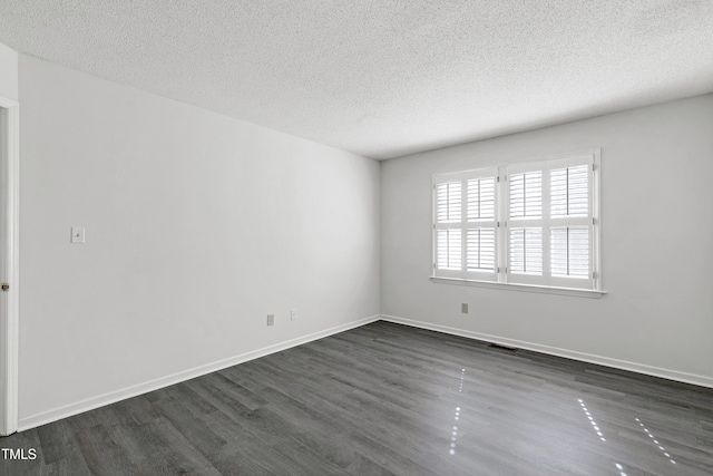 unfurnished room featuring baseboards, a textured ceiling, visible vents, and dark wood-style flooring