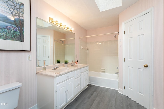 full bathroom featuring a skylight, a sink, toilet, and wood finished floors