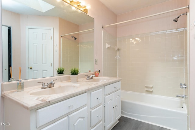 full bathroom with double vanity, a skylight, bathtub / shower combination, and a sink