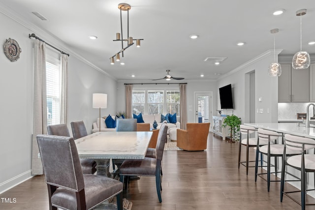 dining area with a wealth of natural light, dark wood-style flooring, and crown molding