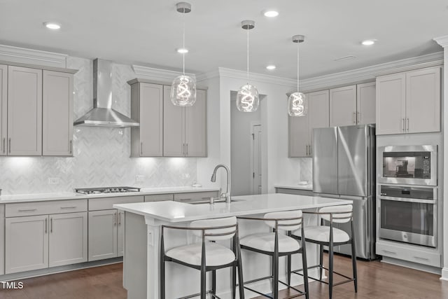 kitchen featuring stainless steel appliances, a sink, light countertops, gray cabinets, and wall chimney exhaust hood