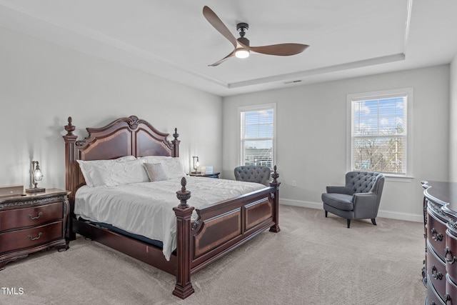 bedroom featuring light colored carpet, a tray ceiling, visible vents, and baseboards