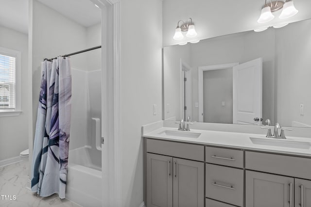 bathroom with marble finish floor, double vanity, a sink, and toilet