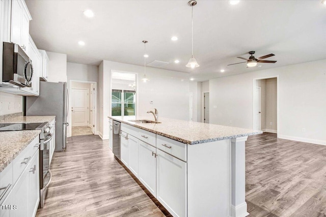 kitchen with light wood finished floors, appliances with stainless steel finishes, white cabinetry, a sink, and an island with sink