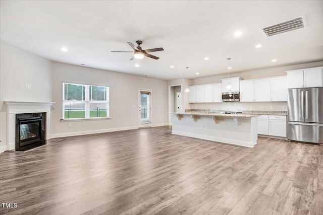 kitchen with open floor plan, appliances with stainless steel finishes, visible vents, and light wood-style floors