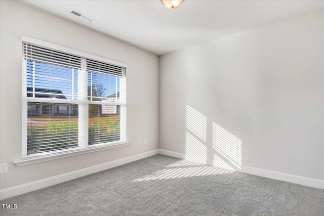 spare room with carpet, visible vents, and baseboards