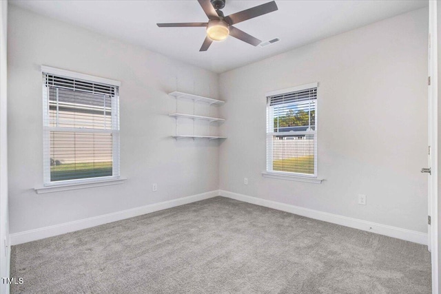 spare room featuring carpet floors, a ceiling fan, visible vents, and baseboards