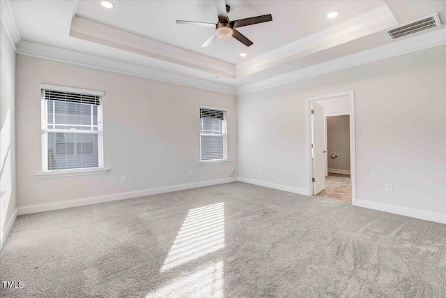 unfurnished bedroom featuring carpet floors, visible vents, a raised ceiling, and ornamental molding