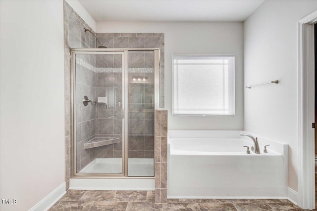 full bathroom featuring a garden tub, a shower stall, and baseboards