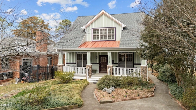 view of front of home with metal roof, a porch, a shingled roof, board and batten siding, and a standing seam roof