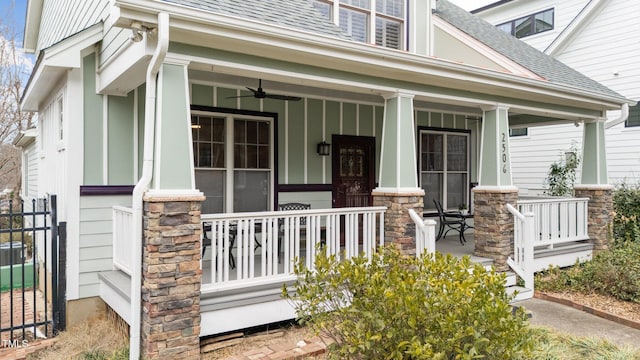 property entrance with covered porch, a shingled roof, stone siding, and a ceiling fan