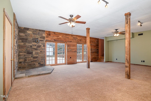 unfurnished living room featuring ornate columns, carpet, visible vents, and wooden walls