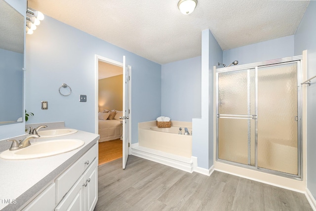 bathroom with a sink, a stall shower, wood finished floors, and a textured ceiling