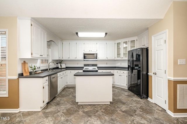 kitchen with appliances with stainless steel finishes, white cabinets, visible vents, and a sink