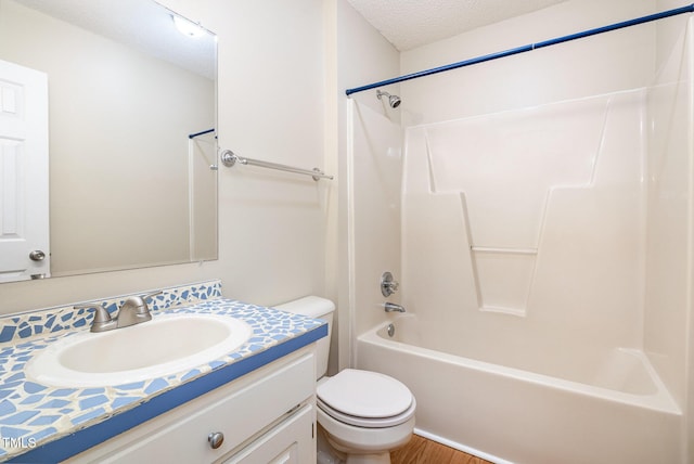 bathroom with a textured ceiling, toilet, wood finished floors, vanity, and shower / bathing tub combination