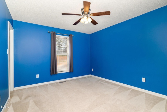 carpeted empty room featuring baseboards, visible vents, ceiling fan, and a textured ceiling