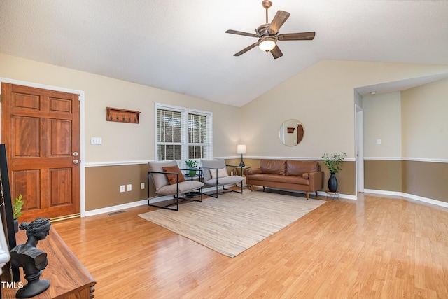 living area with lofted ceiling, ceiling fan, visible vents, baseboards, and light wood finished floors