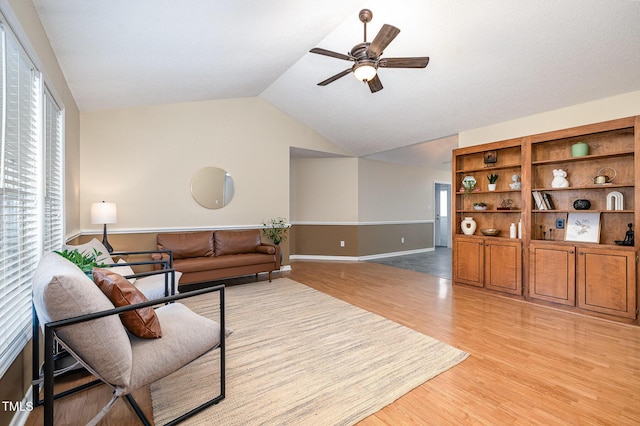 living room with lofted ceiling, light wood-style floors, and a ceiling fan