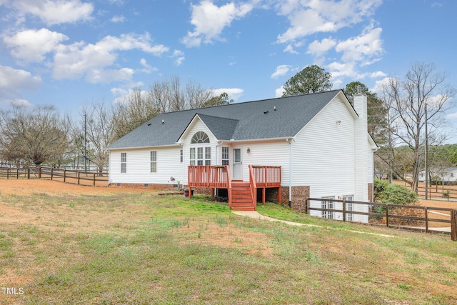 back of property with a yard, a chimney, a shingled roof, a fenced backyard, and a wooden deck