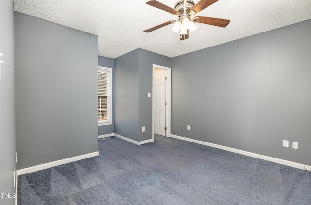 unfurnished room with a ceiling fan, baseboards, dark carpet, and a textured ceiling