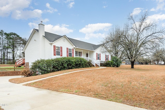 view of front of property featuring a front lawn, a chimney, and a porch