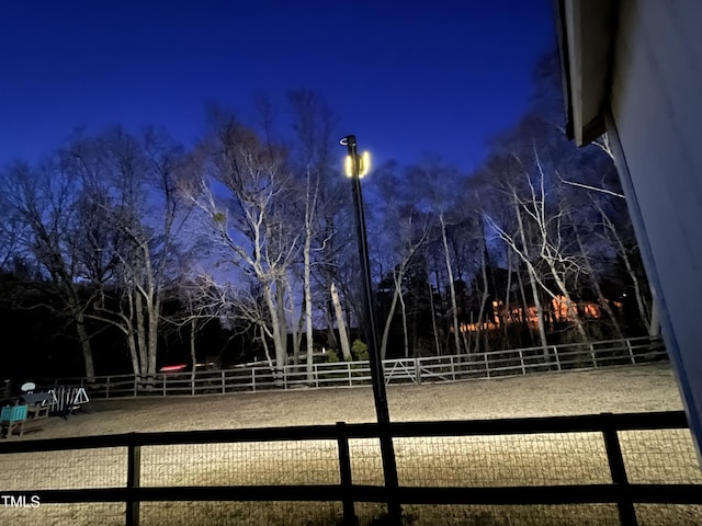 yard at night featuring an enclosed area and fence