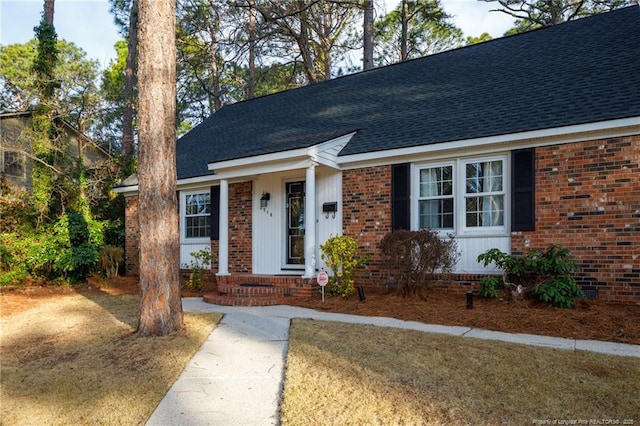 view of front facade with a shingled roof and brick siding