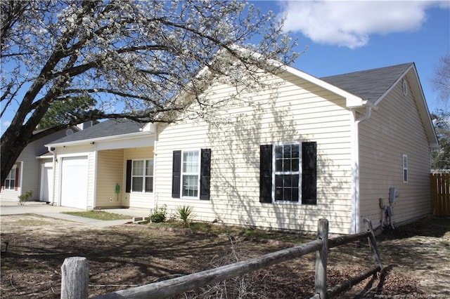 view of front of home with a garage, concrete driveway, and fence