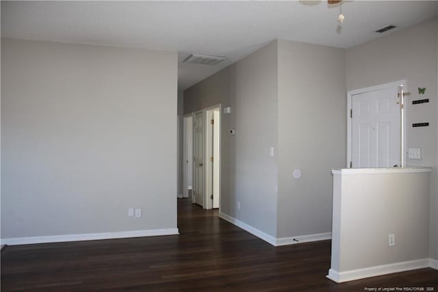 empty room with wood finished floors, visible vents, and baseboards