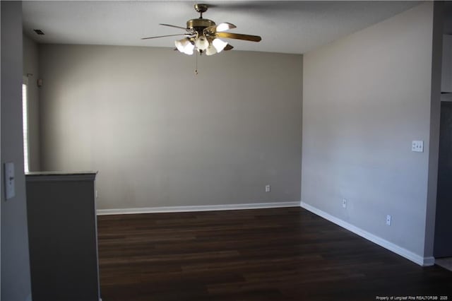 unfurnished room with dark wood-style flooring, ceiling fan, and baseboards