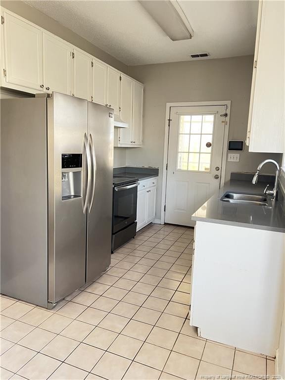 kitchen featuring light tile patterned floors, visible vents, black / electric stove, stainless steel refrigerator with ice dispenser, and a sink