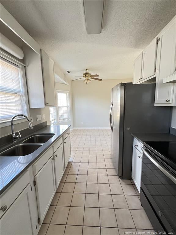 kitchen featuring stainless steel range with electric stovetop, white cabinetry, a sink, and light tile patterned flooring