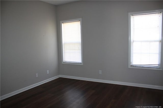 spare room with dark wood finished floors and baseboards