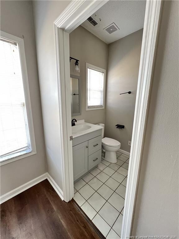 bathroom featuring baseboards, visible vents, vanity, and toilet