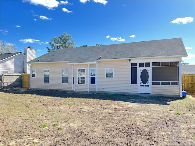 rear view of property featuring a lawn, fence private yard, and a sunroom