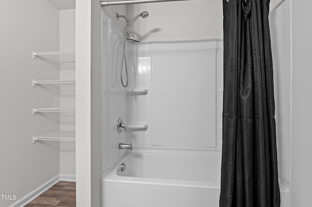 bathroom featuring shower / bath combo, baseboards, and wood finished floors