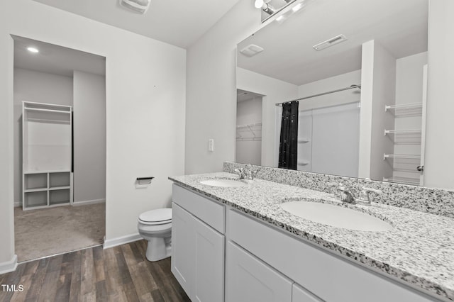 bathroom with toilet, a spacious closet, visible vents, and a sink