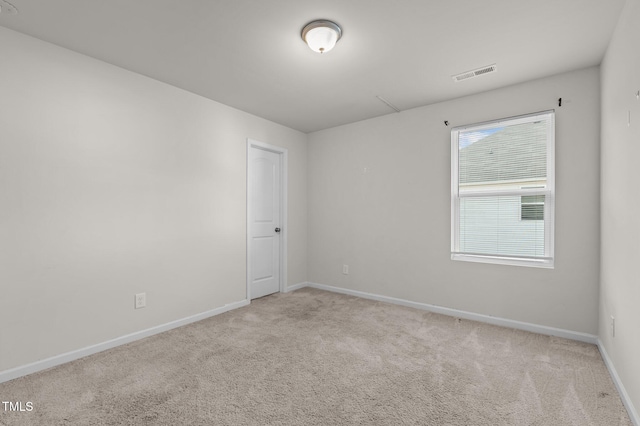 empty room featuring carpet floors, visible vents, and baseboards