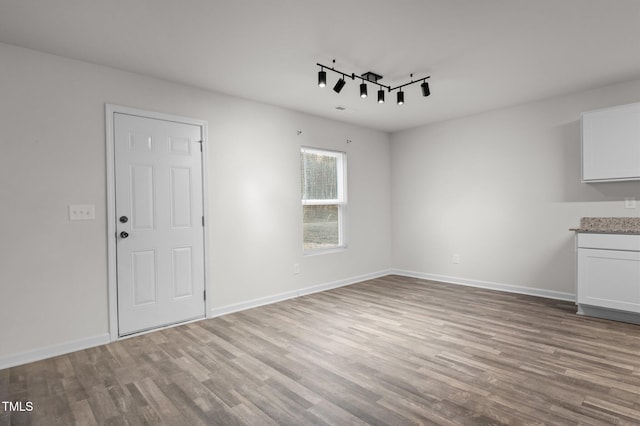 interior space featuring track lighting, baseboards, and wood finished floors