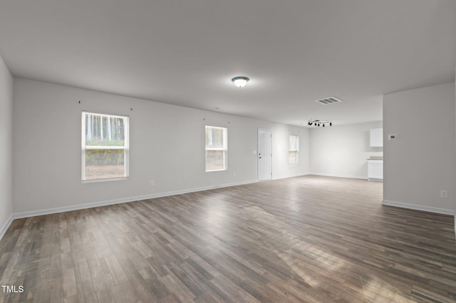 unfurnished room with dark wood-style floors, visible vents, and baseboards