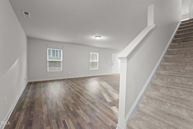 interior space featuring baseboards, stairs, visible vents, and wood finished floors