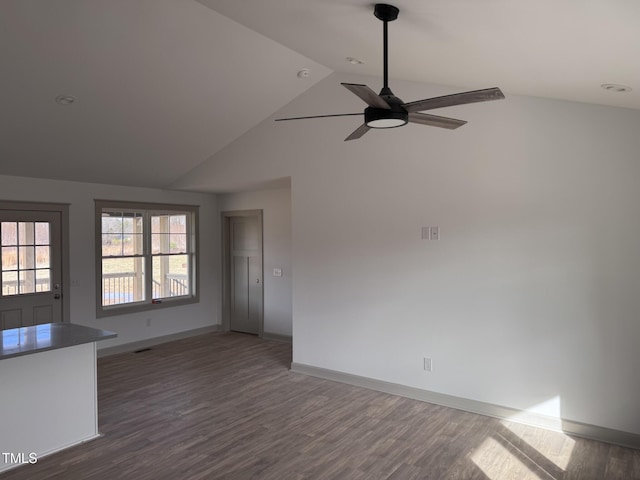 interior space with a ceiling fan, baseboards, vaulted ceiling, and dark wood-style flooring