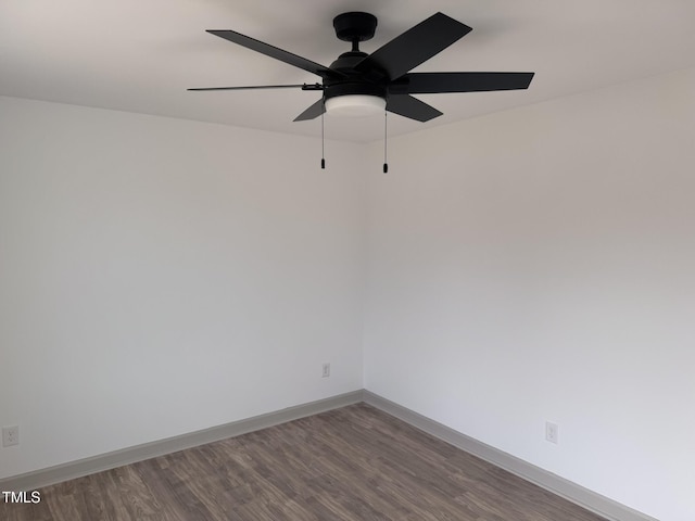 unfurnished room featuring dark wood-type flooring, a ceiling fan, and baseboards